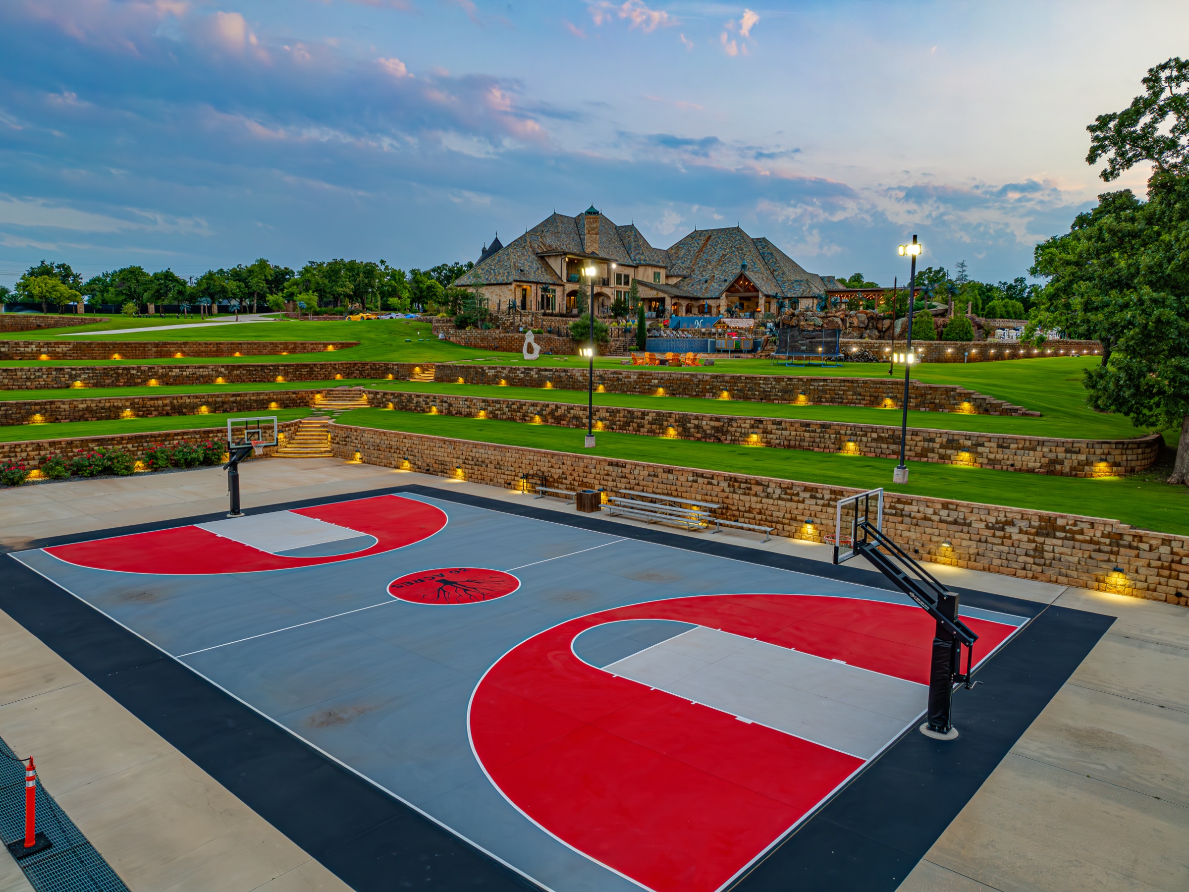 Full-size basketball court at dusk with estate in background